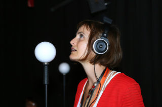 Frau mit Kopfhörern vor schwarzem Hintergrund