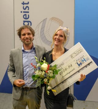 Ein Mann und eine Frau halten glücklich einen Scheck hoch