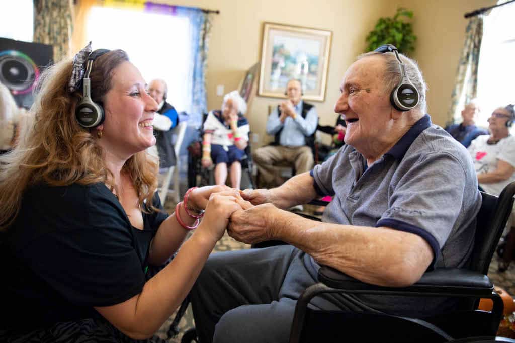 Älterer Mensch trägt Eversound-Kopfhörer in Seniorenheim während Betreuung