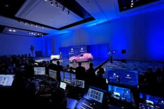 Zwei Volkswagen-PKW auf der Bühne der CES 2024 in Las Vegas; im Vordergrund verschiedene Displays mit Settings