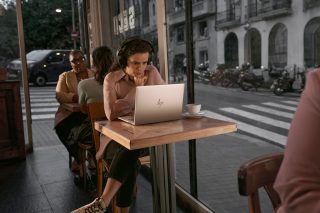 Frau schaut in einem Cafe auf ihren HP-Notebook