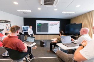 Eine Gruppe von Menschen in einem Schulungsraum mit LED-Wall