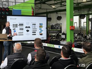 Experte vor großem Bildschirm mit Informationen zu AV over IP vor einer Gruppe von Kursteilnehmern