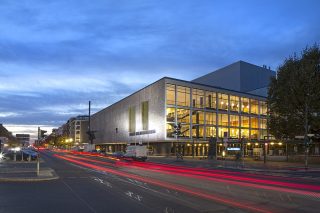 Blick auf das erleuchtete Gebäude der Deutschen Oper Berlin am Abend