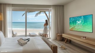 Blick aus einem Hotelzimmer auf einen Strand, ein schickes Display an der Wand