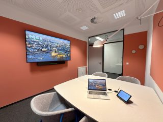 Blick in einen Besprechungsraum mit Tisch und Wand-Display