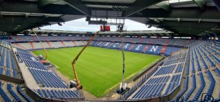 Blick ins Innere des Stadions mit Kränen, die LED-Material am Dach befestigen