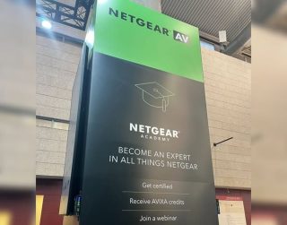 Stele mit grünem Abschnitt mit Schriftzug Netgear und Informationen zur Netgear-Academy auf schwarzem Hintergrund