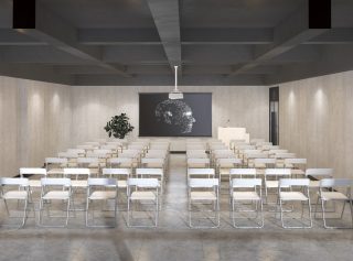 Saal mit leeren Stüheln, Bildschirm an der Wand und Projektor an der Decke