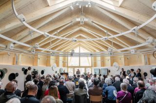 Innenraum mit Publikum und Holzdecke mit Lautsprechern
