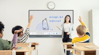 Junge Frau steht interaktiver Tafel in Schulklasse