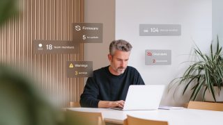 Grauhaariger Mann mittleren Alters vor Notebook mit Sprechblasen um ihn herum