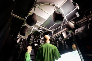 Zwei Demo-Personen im Demo-Raum umgeben von Lautsprechern