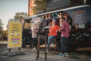 Gruppe von Menschen vor einem Food Truck neben einem Outdoor-Display