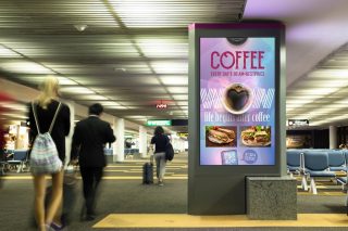 Großes Display , an dem Menschen mit Koffer vorbeigehen