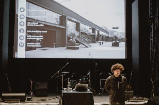 Speaker auf Bühne vor großer Leinwand