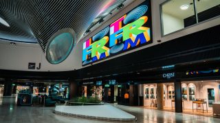Große LED-Wand mit grellbunter Schrift über Shops