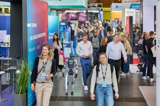 Besucher auf der Leantec, ein humanoider Roboter unter ihnen