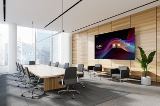 Besprechungsraum mit langeem Tisch und großem Display an der Wand rechts