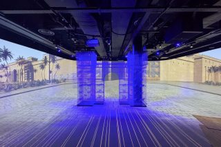 Immersiver Ausstellungsraum von Timewalk mit großflächigen historischen Projektionen und transparenten Raumstrukturen.